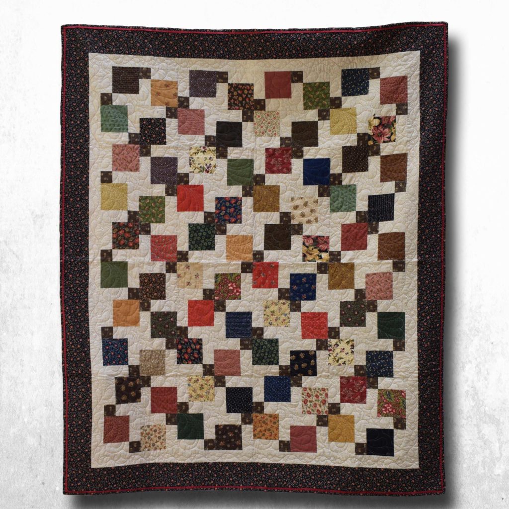 Handmade patchwork in brown and dark blue, with red and cream accents.
