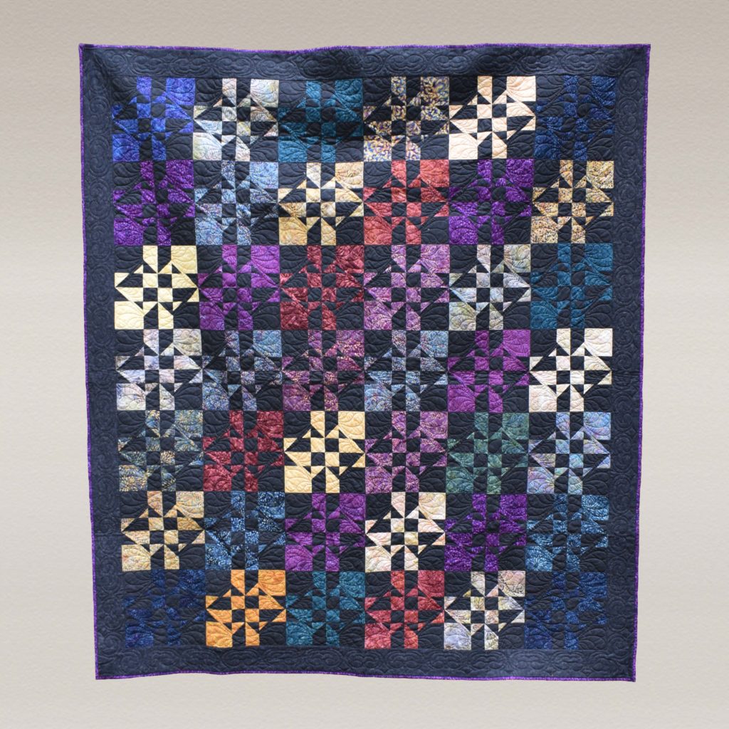 Dramatic modern geometric quilt in black and bright gemstone colors.