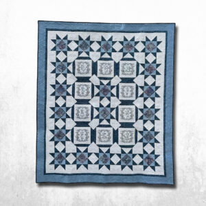 Handmade blue and white embroidered quilt hanging outdoors, featuring vintage-look boys in garden scenes, star patchwork blocks, floral accent centers, and wide blue borders.